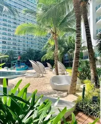 a resort with palm trees and chairs and a building at Sabrina'sCrib Apartment 2BR by Azure Residences Near Manila International Airport in Manila