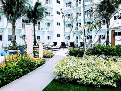 a walkway in front of a building with palm trees at Condominium Shore 1 Mall of Asia in Manila