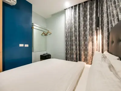 a bedroom with a white bed and a blue curtain at Bay Area Suites Manila in Manila