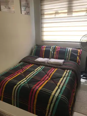 a bed with a plaid blanket and a window at Shanilyn Residency Urban Deca Towers EDSA mandaluyong Unlimited INTERNET AND NETFLIX in Manila