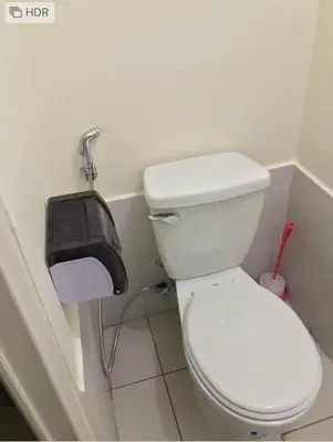 a bathroom with a toilet with a toilet paper dispenser at Shanilyn Residency Urban Deca Towers EDSA mandaluyong Unlimited INTERNET AND NETFLIX in Manila