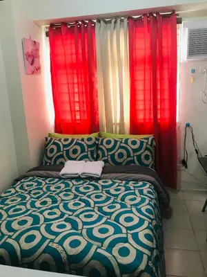 a bedroom with red curtains and a bed with a bedspread at Shanilyn Residency Urban Deca Towers EDSA mandaluyong Unlimited INTERNET AND NETFLIX in Manila
