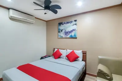 a bedroom with a bed with red pillows and a ceiling fan at DG Grami Hotel in Manila