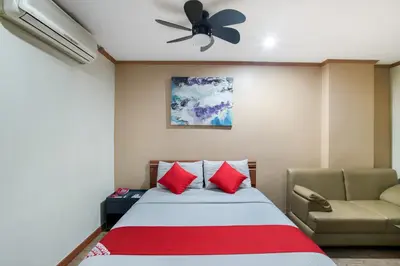 a bedroom with a bed and a couch and a ceiling fan at DG Grami Hotel in Manila