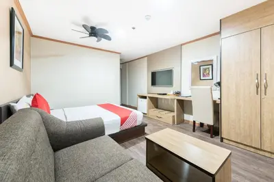 a hotel room with a couch and a desk at DG Grami Hotel in Manila