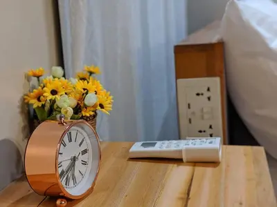 a clock sitting next to a vase of flowers on a table at Studio Condo NAIA Airport Terminal 3 Newport City Casino in Manila