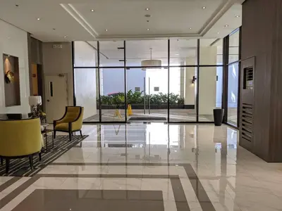 a lobby with a glass table and yellow chairs at Studio Condo NAIA Airport Terminal 3 Newport City Casino in Manila