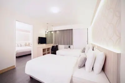 a white bedroom with two beds and a tv at The Charter House in Manila