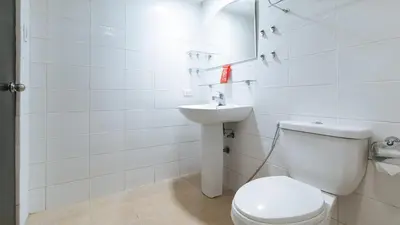 a white bathroom with a toilet and a sink at RedDoorz at Kassel Residences Parañaque in Manila