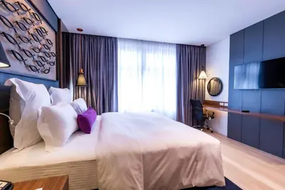 a bedroom with a large bed with white sheets and purple pillows at Coro Hotel in Manila