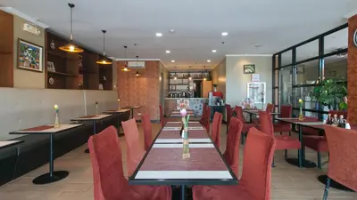 a restaurant with a long table and red chairs at RedDoorz Plus at MM Hotel Las Pinas former RedDoorz Plus Near Bamboo Organ in Manila