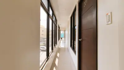 a corridor of a building with windows and a door at RedDoorz Plus at Evangelista Street Makati in Manila