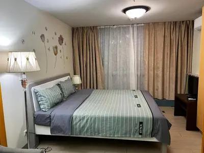 a bedroom with a bed and a lamp and a window at ONE UPTOWN RESIDENCE in Manila