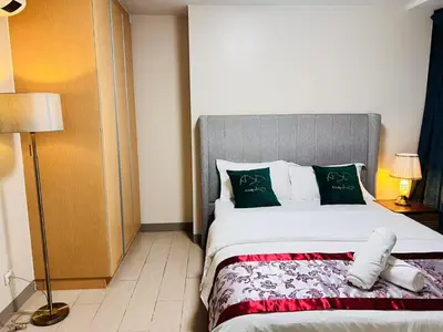a bedroom with a bed with green and white pillows at ONE UPTOWN RESIDENCES in Manila