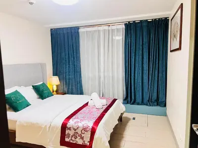 a bedroom with a large bed with blue curtains at ONE UPTOWN RESIDENCES in Manila