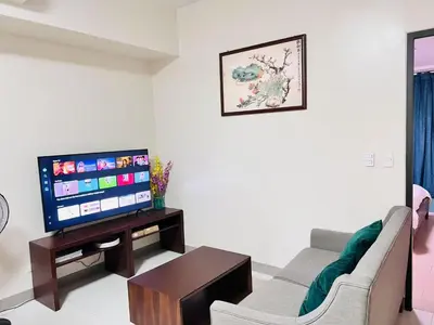 a living room with a couch and a tv at ONE UPTOWN RESIDENCES in Manila