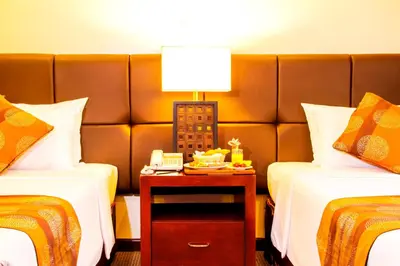 a hotel room with two beds and a lamp on a table at AIM Conference Center in Manila
