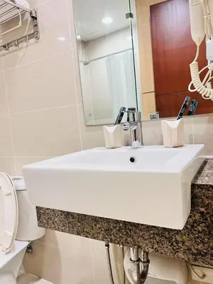 a bathroom with a white sink and a toilet at ONE UPTOWN residence SW14M 9TH AVENUE ST \u516c\u5bd3 in Manila