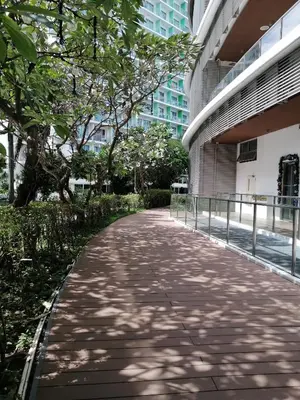 a sidewalk in front of a building with trees at AZURE Urban Resort Residences 1BR Condo with huge wavepool & man-made beach near Airport in Manila