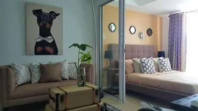 a living room with a couch and a dog picture on the wall at AZURE Urban Resort Residences 1BR Condo with huge wavepool & man-made beach near Airport in Manila