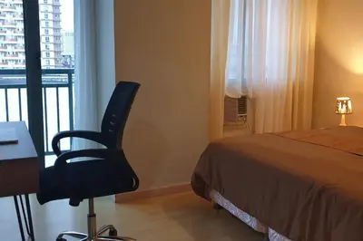 a bedroom with a bed and a desk and a chair at MANDALUYONG 2 Br w 2 Queen, 50HDtv across Shangrila Mall in Manila