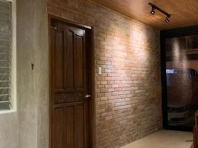 a room with a brick wall and a wooden door at The Hub District Garden Suites in Manila