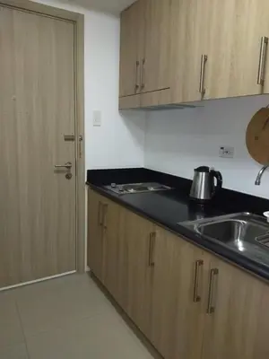 a kitchen with wooden cabinets and a sink and a door at Jones Shore Residences in Manila