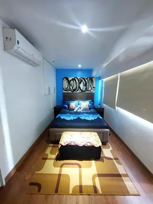 a bedroom with a bed with a blue headboard at Fort Victoria BGC 2 Bedrooms in Manila