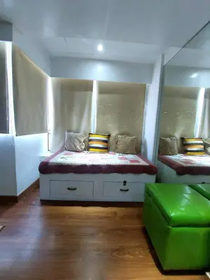 a bedroom with two beds and a green ottoman at Fort Victoria BGC 2 Bedrooms in Manila