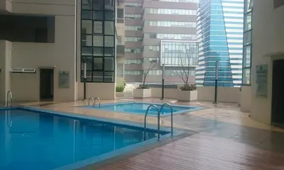 a large swimming pool in a building with a tall building at Fort Victoria BGC 2 Bedrooms in Manila