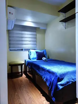 a bedroom with a blue bed and a table at Fort Victoria BGC 2 Bedrooms in Manila