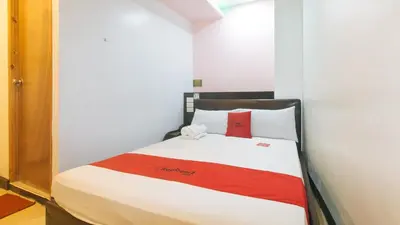 a bedroom with a bed with a red and white blanket at RedDoorz at Ranchotel Alabang in Manila