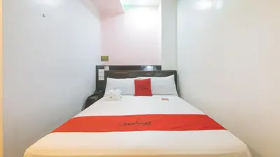a bed in a room with a red and white blanket at RedDoorz at Ranchotel Alabang in Manila
