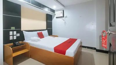 a bedroom with a bed with a red and white blanket at RedDoorz at Ranchotel Alabang in Manila