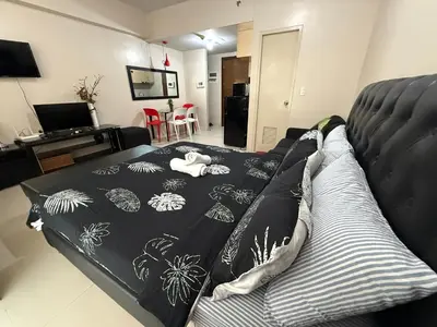 a bed with a black and white blanket on it at One Palm Tree Villas across NAIA-T3 in Manila