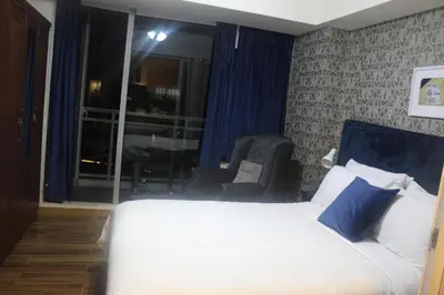 a bedroom with a bed and a chair and a window at Azure C3 Balcony Wifi near mall airport in Manila