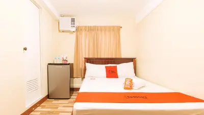 a bedroom with a bed with a orange and white blanket at RedDoorz near PNR Espana Station in Manila