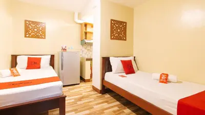 a room with two beds with red pillows at RedDoorz near PNR Espana Station in Manila