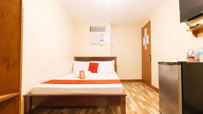 a small room with a bed and a television at RedDoorz near PNR Espana Station in Manila