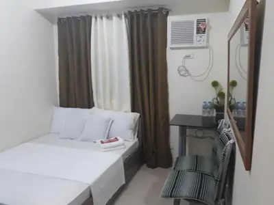 a small room with a bed and a desk and a window at Edsa Urban Deca Tower Condo Unit with Wifi and Netflix in Manila