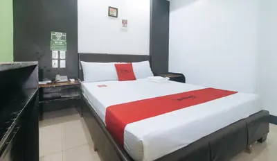 a bedroom with a large bed with a red blanket at RedDoorz at Ranchotel Bayanan Alabang in Manila