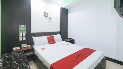 a bedroom with a bed with a red blanket at RedDoorz at Ranchotel Bayanan Alabang in Manila