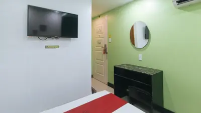 a room with a bed and a tv on a wall at RedDoorz at Ranchotel Bayanan Alabang in Manila