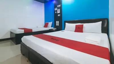 two beds in a room with red and white at RedDoorz at Ranchotel Bayanan Alabang in Manila