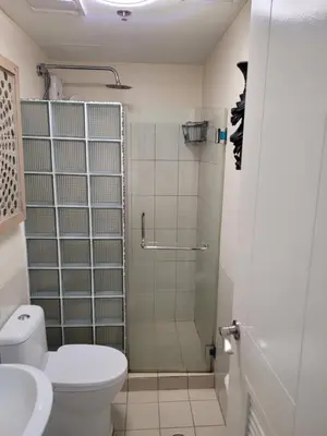 a bathroom with a shower and a toilet and a sink at Juja's place in Manila