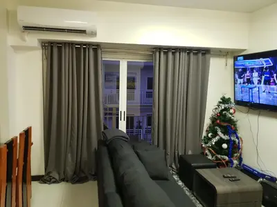 a living room with a couch and a christmas tree at Cucun's place in Manila