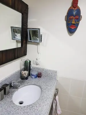 a bathroom with a sink and a mask on the wall at Cucun's place in Manila