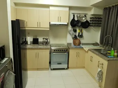 a kitchen with wooden cabinets and a stove top oven at Cucun's place in Manila
