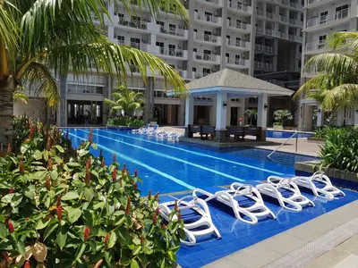 a swimming pool with white lounge chairs next to a building at Cucun's place in Manila