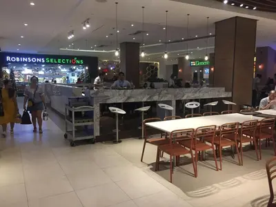 a restaurant with tables and chairs in a mall at Modern Stylish Condo in Morgan Suites McKinley with Wi-Fi in Manila